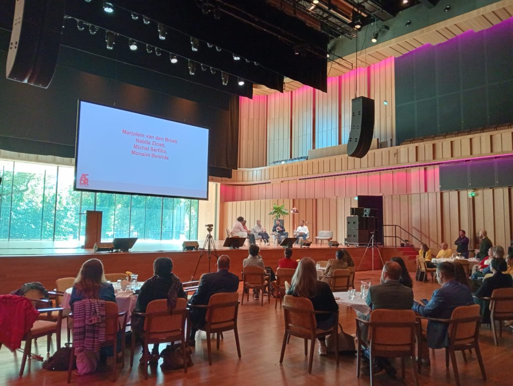 Overzichtfoto van mensen in de zaal tijdens het symposium