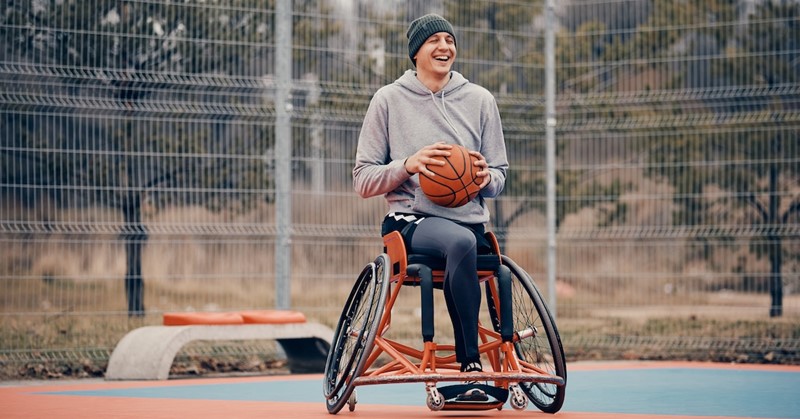 jongen met basketball in rolstoel buiten in de kou